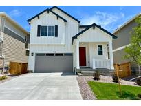 Charming two-story home featuring a modern farmhouse design, gray garage door and a bright red front door at 9286 Telluride Ct, Commerce City, CO 80022
