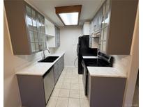 Galley kitchen with ample cabinetry, including glass-front cabinets, and sleek, white countertops at 14751 E Tennessee Dr # 213, Aurora, CO 80012