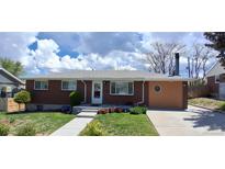 Charming brick home featuring a well-manicured front yard, inviting entrance, and quaint landscaping at 8338 Charles Way, Denver, CO 80221