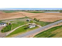 Expansive aerial view of a charming country home with lush green lawns and surrounding farmland at 19810 County Road 1, Berthoud, CO 80513