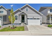 Charming home featuring a two-car garage, well-manicured lawn, and an inviting covered front porch at 27853 E 8Th Ave, Aurora, CO 80018