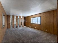 Spacious living room features carpeted floors, wood paneled walls, and a large window at 2115 W 90Th Ave, Federal Heights, CO 80260