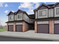 Three-unit townhome building with attached garages and brick accents at 10810 W 63Rd Ave # C, Arvada, CO 80004