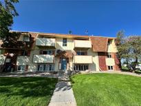 Townhouse complex with balconies, sidewalk and green lawn against a clear blue sky at 10211 Ura Ln # 7-108, Thornton, CO 80260