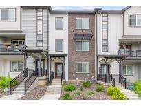 Modern townhome exterior showcasing gray and white siding with brick accents, complemented by well-maintained landscaping at 1918 W 165Th Way, Broomfield, CO 80023