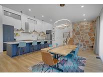 Open-concept kitchen and dining area featuring a large island and stone accent wall at 6260 Lamar St, Arvada, CO 80003