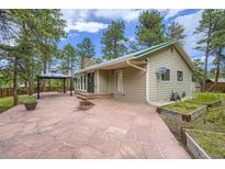 Backyard patio featuring stone pavers, a gazebo, garden beds, and mature pine trees at 26732 Main St, Conifer, CO 80433