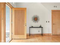 Bright entryway with an open front door, light wood floors, modern table and decorative art at 1942 Kentmere Dr, Longmont, CO 80504