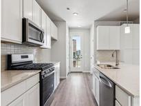 Modern kitchen boasts stainless steel appliances, light countertops, white cabinets, and wood flooring at 451 Interlocken Blvd # 104, Broomfield, CO 80021