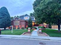 Charming brick home featuring lush landscaping, well-lit walkway, and a manicured lawn at 3810 E White Bay Dr, Highlands Ranch, CO 80126