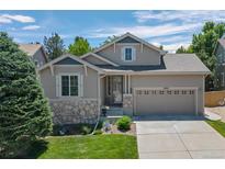 Charming two-story home with stone accents, a well-manicured lawn, and an attached two-car garage at 3092 Fox Sedge Pl, Highlands Ranch, CO 80126