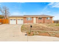 Charming brick home featuring an attached two-car garage and well-maintained front yard at 7162 Quay St, Arvada, CO 80003