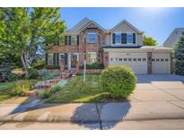 Beautiful two-story brick home with a three-car garage and landscaped front yard at 9602 S Hackberry St, Highlands Ranch, CO 80129
