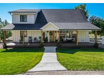 Charming two-story farmhouse with welcoming front porch, verdant lawn and welcoming entrance at 6242 W Lakeside Ct, Littleton, CO 80125