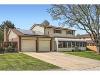 Charming two-story home with a long driveway, a two-car garage, and a sunroom at 10223 W 77Th Dr, Arvada, CO 80005