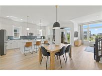Bright, open kitchen and dining area with modern white cabinets, stainless appliances, and wood floors at 16722 Shoshone St, Broomfield, CO 80023