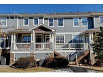 Gray townhome with a front porch, staircase, and landscaping at 9343 Amison Cir # 103, Parker, CO 80134