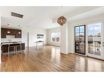 Open-concept living space with hardwood floors, kitchen island, and balcony access at 410 Acoma St # 605, Denver, CO 80204