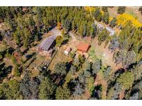 Stunning aerial view of a mountain property with a home, garage, barn, and lush trees at 28553 Birch Ln, Conifer, CO 80433