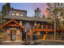 Charming exterior showcasing stone accents, a wooden deck, and rustic design, nestled among tall pine trees at 142 High Point Dr, Breckenridge, CO 80424
