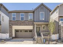 Charming two-story home with a gray exterior, stone accents, and an attached two-car garage at 2128 S Haleyville Way, Aurora, CO 80018