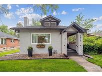 Charming home featuring a well-manicured lawn, black planters, and an inviting covered front porch at 1870 S Ogden St, Denver, CO 80210