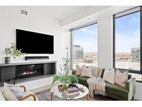 Bright living room featuring a cozy fireplace, comfortable seating, and expansive windows with stunning city views at 1750 Wewatta St # 1825, Denver, CO 80202
