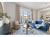 Bright living room features a modern blue sofa, round wooden table, and large windows with access to a private balcony at 410 Acoma St # 309, Denver, CO 80204
