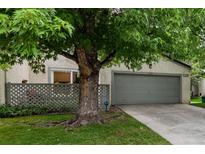 Charming home exterior with large tree, lush lawn, and a gray two-car garage at 1633 S Trenton St, Denver, CO 80231