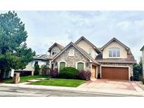 Charming two-story home with stone accents, a well-manicured lawn, and an attached two car garage at 16713 W Archer Ave, Golden, CO 80401