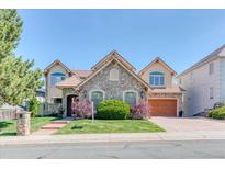 Charming stone-accented home featuring a tile roof, manicured lawn and mature trees at 16713 W Archer Ave, Golden, CO 80401