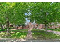 Charming brick home with mature trees and a well-manicured lawn offers great curb appeal at 2065 Leyden St, Denver, CO 80207