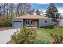Charming blue single-story home featuring a manicured lawn, gray garage, and cozy front porch with seating at 3230 Vance St, Wheat Ridge, CO 80033