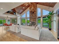 Bright living room featuring vaulted wood ceilings, stone fireplace, and expansive windows overlooking the lush backyard at 6234 Nautique Cir, Larkspur, CO 80118