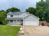 Charming two-story home with attached garage, solar panels, well maintained lawn, and front porch swing at 14828 E Pacific Pl, Aurora, CO 80014
