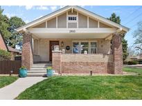 Charming brick home featuring a cozy front porch and a well-manicured lawn at 2900 Clermont St, Denver, CO 80207