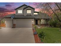 Charming two-story home featuring a two-car garage, well-manicured lawn, and colorful dusk sky at 17522 E Dewberry Dr, Parker, CO 80134
