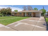 Single story home featuring a brick facade, covered parking and mature landscaping at 4728 Dover St, Wheat Ridge, CO 80033