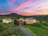 Stunning aerial view of home featuring a landscaped yard, long driveway, guest house, and beautiful sunset backdrop at 3485 Park Ridge Rd, Sedalia, CO 80135