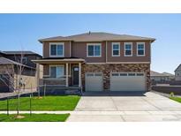 Two-story home with brick and siding, a well-manicured lawn, and an attached three-car garage at 1860 Chaffee Crest Dr, Berthoud, CO 80513