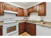 Well-lit kitchen features wood cabinetry, stone counters, and modern white oven and dishwasher at 610 S Alton Way # 8D, Denver, CO 80247