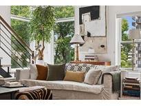 Bright living room featuring a comfortable sofa, art, large windows and a leafy green tree at 790 N Clarkson St # 206, Denver, CO 80218