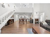 Bright open-concept living room with wood floors, staircase, and direct access to the kitchen and dining area at 23551 Genesee Village Rd # H, Golden, CO 80401