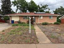 Charming brick home with a red roof, solar panels, and an attached garage on a grassy lot at 1761 W 82Nd Pl, Denver, CO 80221