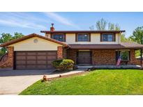 Charming two-story home with brick and vinyl siding, complemented by a well-manicured lawn and mature trees at 1354 S Macon St, Aurora, CO 80012