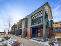 Modern townhome with brick and green siding, private balcony, and snow-covered walkway at 11267 Central Ct, Broomfield, CO 80021