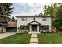 Charming two-story home with manicured lawn, lush trees, and inviting entryway at 3930 S Hillcrest Dr, Denver, CO 80237