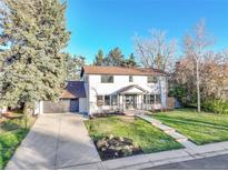 Charming two-story home featuring a well-manicured lawn, a gray attached garage, and a walkway leading to the front door at 3930 S Hillcrest Dr, Denver, CO 80237