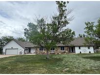 Charming home featuring stone accents, mature trees, and a spacious front yard at 22400 County Road 10, Hudson, CO 80642