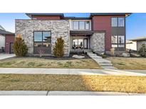 Modern home features a stone facade, multiple windows, and professional landscaping at 6603 Canyonpoint Rd, Castle Pines, CO 80108